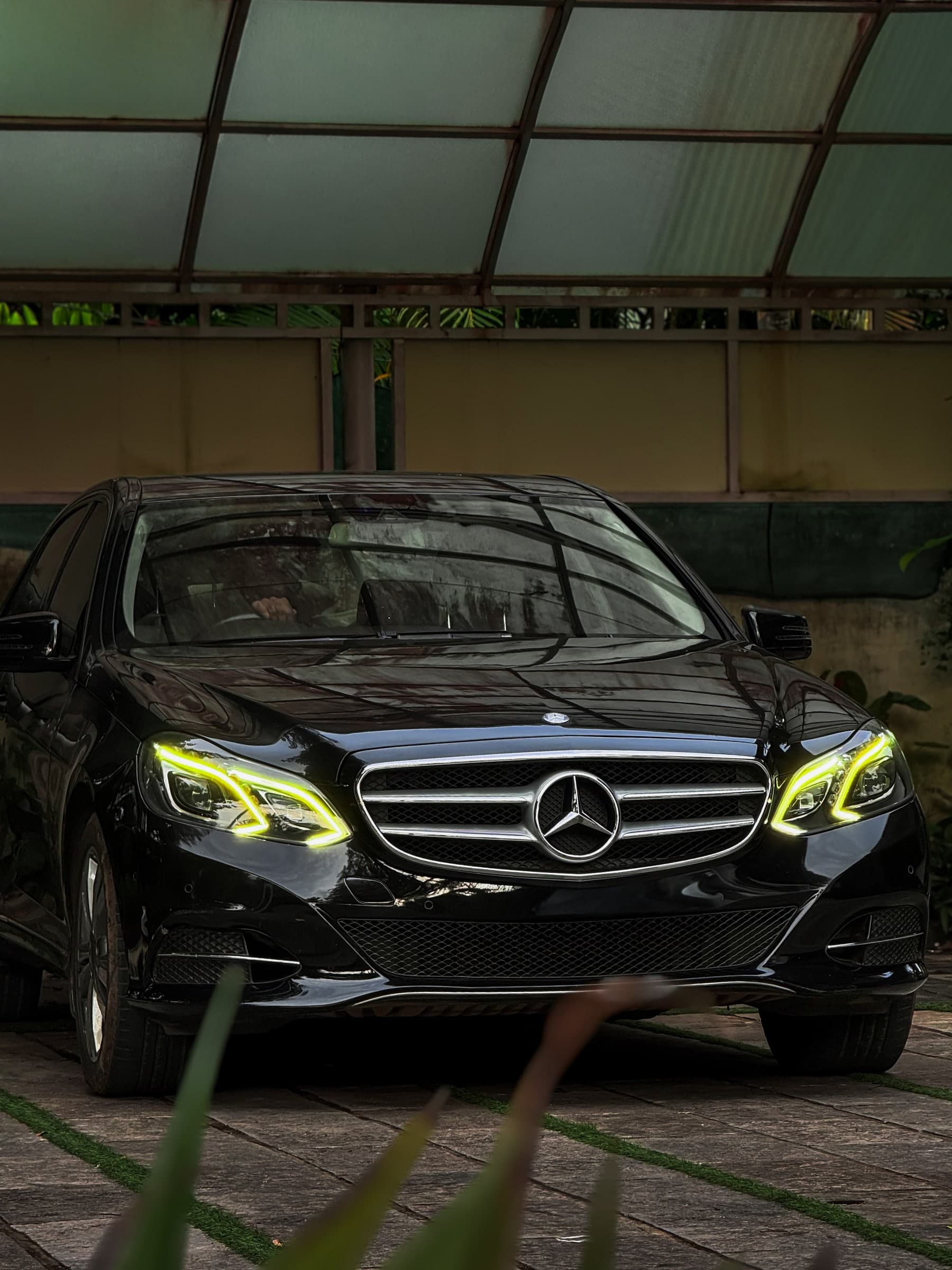 Front view of a black Mercedes with its headlights illuminated