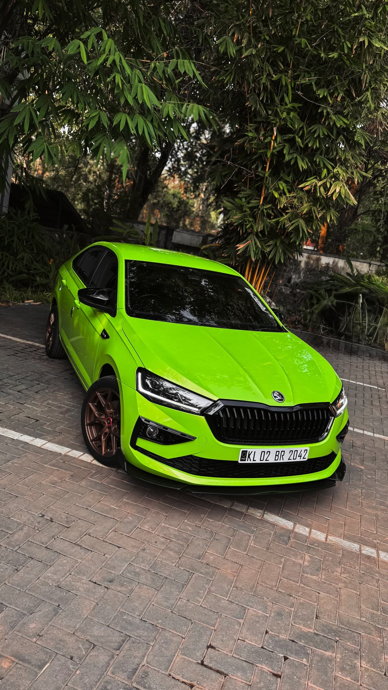 Bright green sedan beneath dense trees in a tilted composition